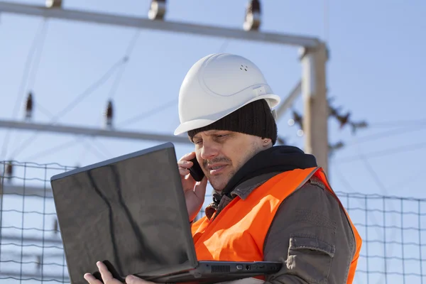 Elektriker mit PC und Handy in der Nähe des Umspannwerks — Stockfoto