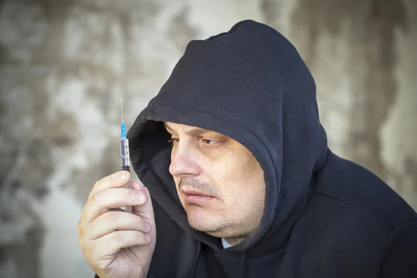 Drugs verslaafde mannen kijkt naar de spuit in de handen — Stockfoto