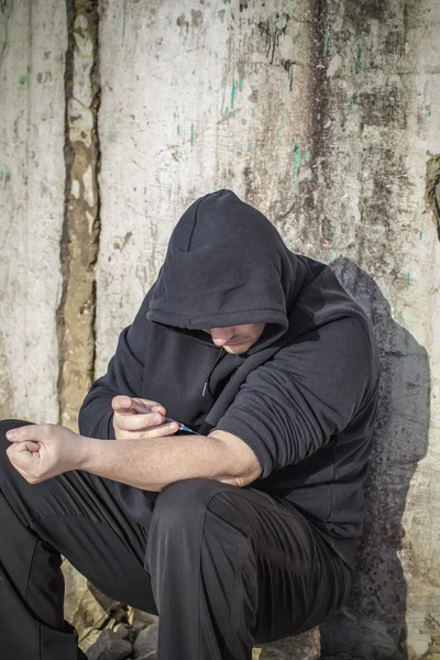 Homem viciado em drogas com seringa nas mãos perto da parede — Fotografia de Stock