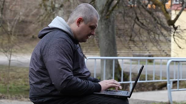 Homme avec PC sur un banc dans le parc — Video