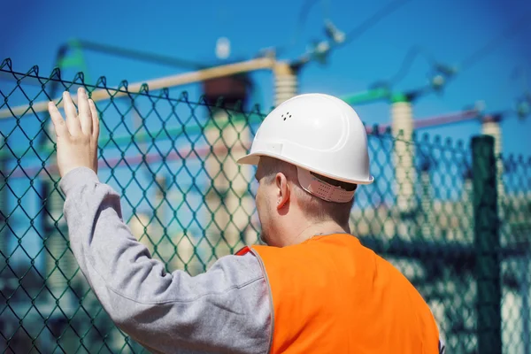 Electrical engineer touched a hand to the fence at the electric substation — Stock Photo, Image