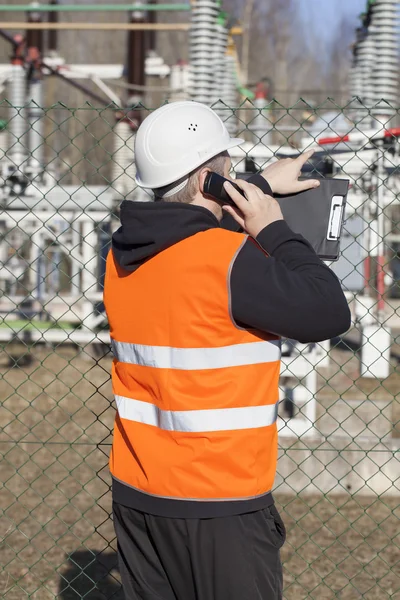 Ingegnere elettrico che parla al cellulare vicino alle sottostazioni elettriche — Foto Stock