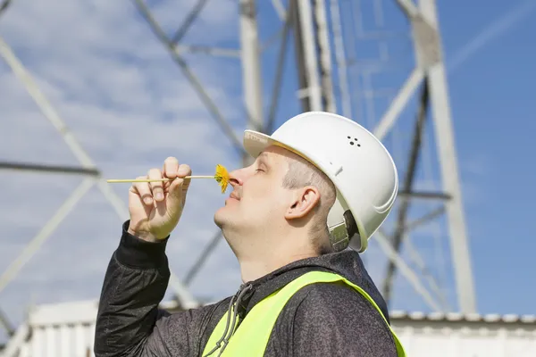 Ingeniero con un diente de león cerca de la nariz en el fondo de la torre gsm — Foto de Stock