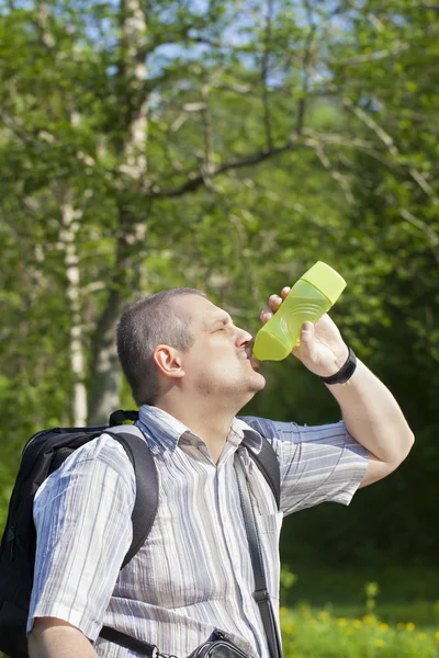 ハイカーは森のトレイルにボトルから水を飲む — ストック写真