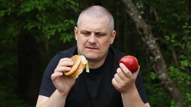 El hombre no puede elegir qué comer manzana o hamburguesa episodio 1 — Vídeo de stock