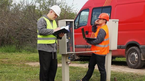 Elektriciens met pc en map in de buurt van schakelbord aflevering een — Stockvideo