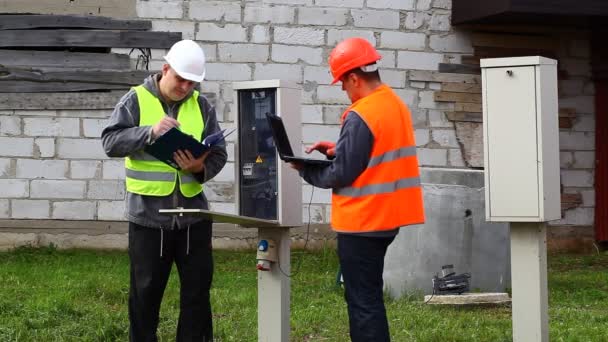 Electricistas con PC y carpeta cerca de centralita episodio 5 — Vídeos de Stock