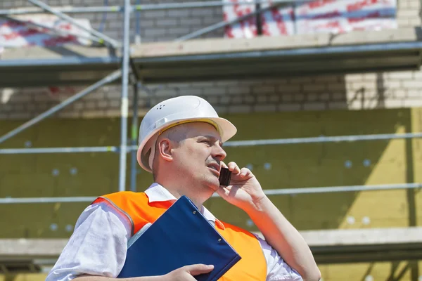 Správce stavby mluví po telefonu v blízkosti lešení — Stock fotografie