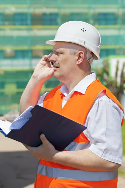 Construction engineer with folder near the scaffolding — Stock Photo, Image