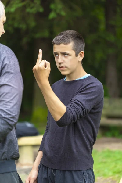 Boy showing middle finger to adult — Stock Photo, Image