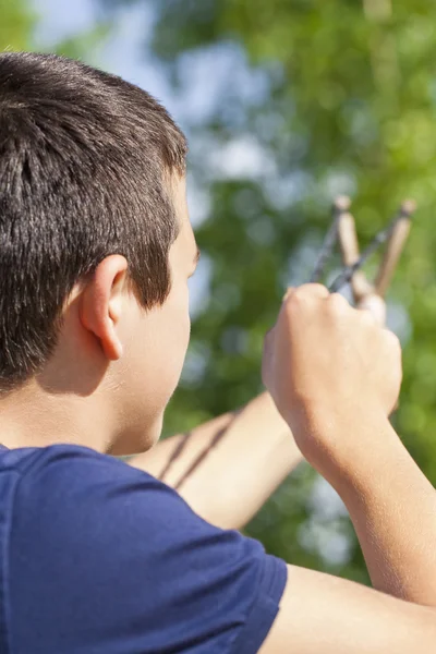 Boy with a slingshot aim to the tree — Stock Photo, Image