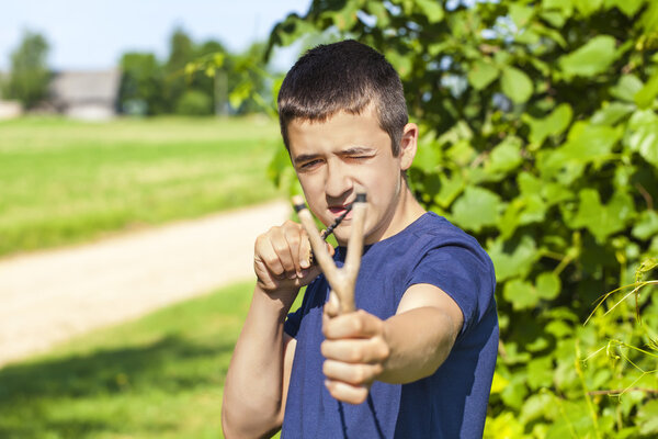 Boy with a slingshot at outdoors in summer
