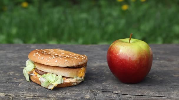 Ruce muže poblíž burger a jablko — Stock video