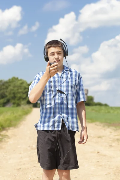 Jongen met hoofdtelefoon en microfoon op landelijke weg in de zomer — Stockfoto