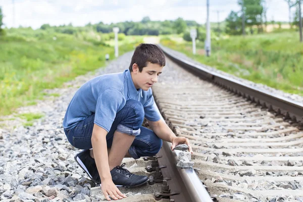 Boy puts stones on railway tracks — Stock Photo, Image