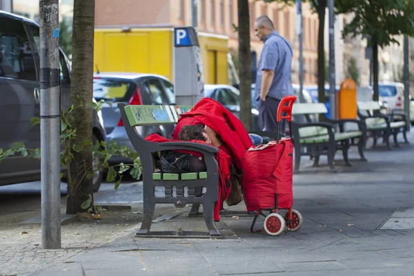 Sans-abri dormant sur un banc dans la rue — Photo