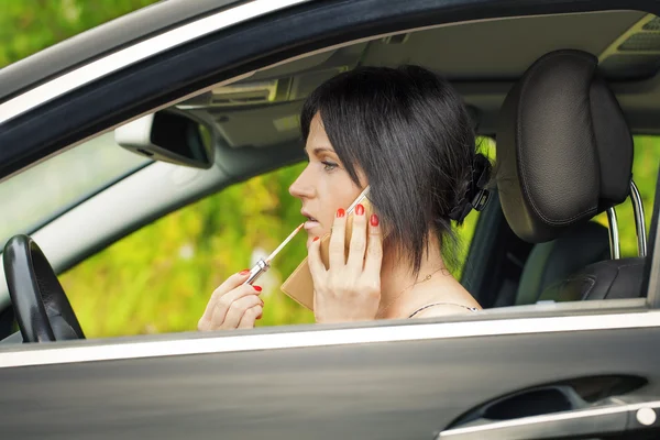 Femme avec le rouge à lèvres et le téléphone portable dans la voiture — Photo
