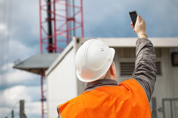 Ingeniero con el teléfono celular cerca de la torre gsm — Foto de Stock