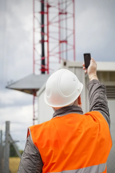 Pracownik z telefonów komórkowych w pobliżu wieży gsm przed deszczem — Zdjęcie stockowe