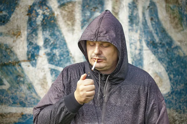 Homem com cigarro no fundo da parede velha — Fotografia de Stock