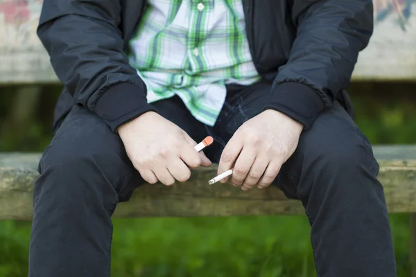Człowiek z papierosa na zewnątrz na ławce — Zdjęcie stockowe