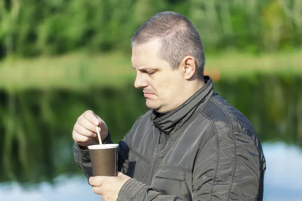 Человек с кофе возле реки — стоковое фото