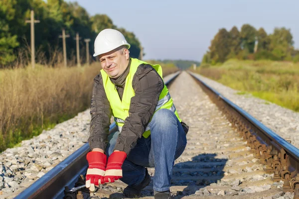 Operaio ferroviario con chiave regolabile su rotaia — Foto Stock