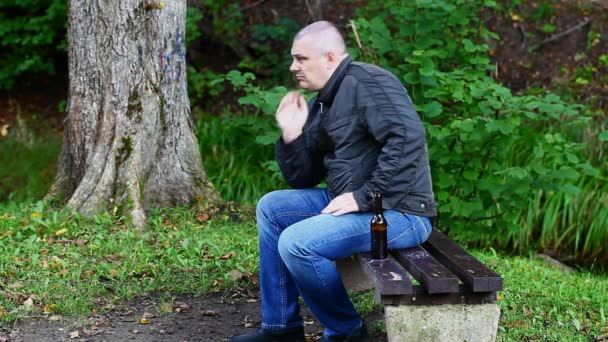 Man met een fles in het park op een bankje aflevering 4 — Stockvideo