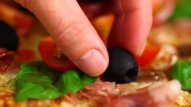 kadın zeytin pizza üzerine koyar.