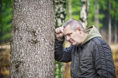 Depressed man leaning on a tree episode 1 clipart