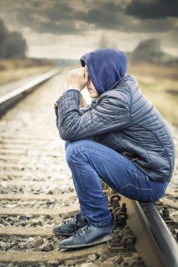 Sorrowful boy on the railway clipart