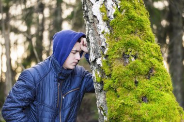 Kederli çocuk ağaca yaslanmış