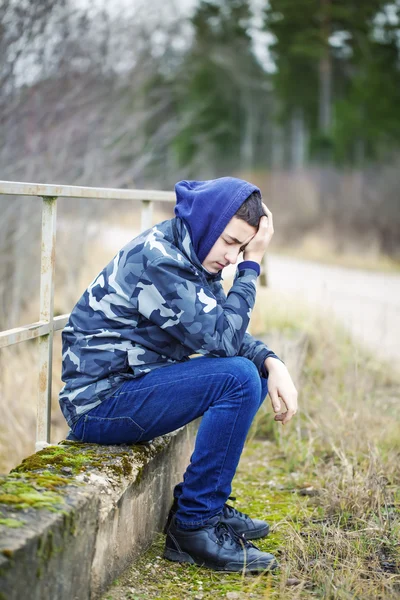 Sorrowful boy on the bridge near road — Stock Photo, Image