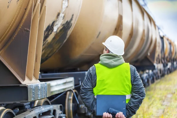 Spoorweg werknemer met map in de buurt van de tankwagons — Stockfoto