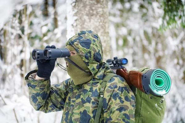 Jager met verrekijkers en optische geweer in bos — Stockfoto