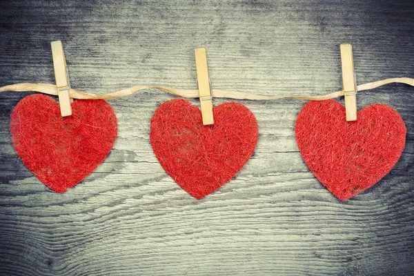 Three hearts hanging on a wooden boards background — Stock Photo, Image
