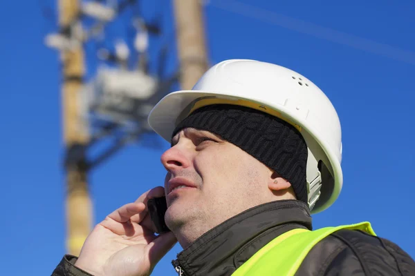 Elektrotechnisch ingenieur met mobiele telefoon in de buurt van transformator — Stockfoto