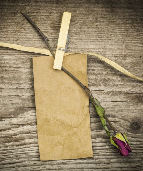 Papper märka med torkad ros på en gammal träskivor — Stockfoto