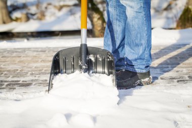 Man with a snow shovel on the trails clipart