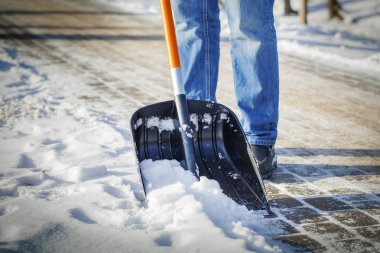 Man with snow shovel cleans sidewalks in winter clipart