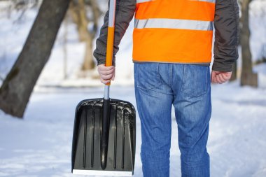 Man with a snow shovel on the sidewalk in winter clipart