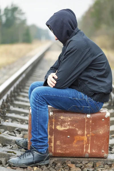 Teenage boy with a suitcase on the railway in rainy day — Stock Photo, Image
