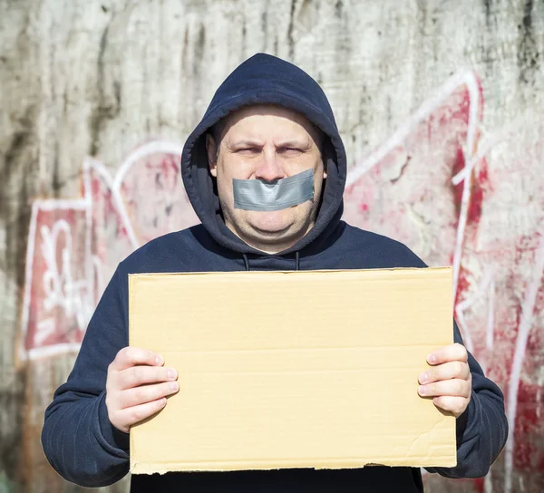 Demonstrator met een tape op een mond en poster in handen — Stockfoto