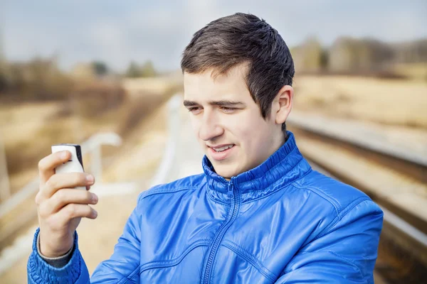 Teen s mobilní telefon na železnici — Stock fotografie