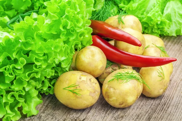 Fresh potatoes with lettuce and peppers on table — Stock Photo, Image