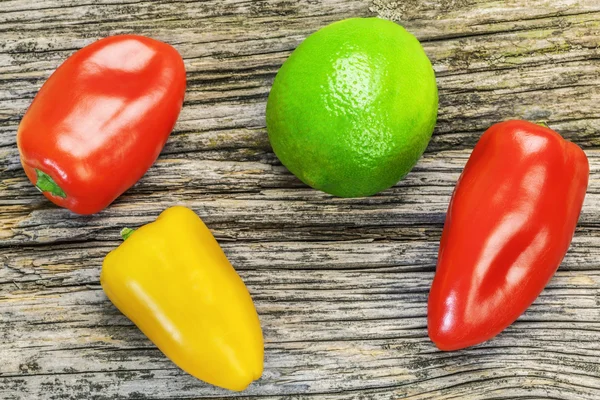 Pimientos con lima sobre tabla de madera vieja — Foto de Stock