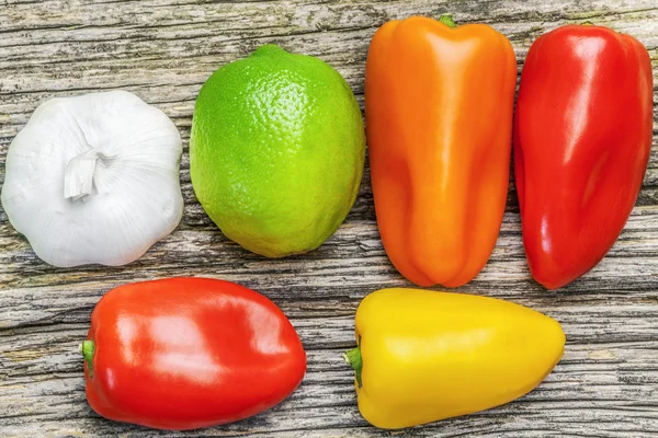 Papriky, česnek a citron na staré dřevěné desce — Stock fotografie