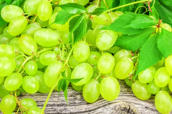 Green grapes with leaves on a old wooden board — Stock Photo, Image