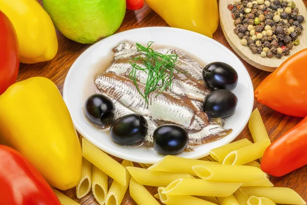 Anchovy fillets with olives and vegetables around on a table — Stock Photo, Image