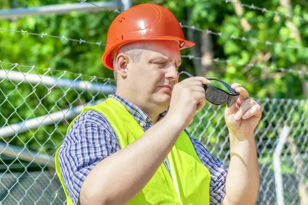 Arbetare med solglasögon nära stängslet — Stockfoto